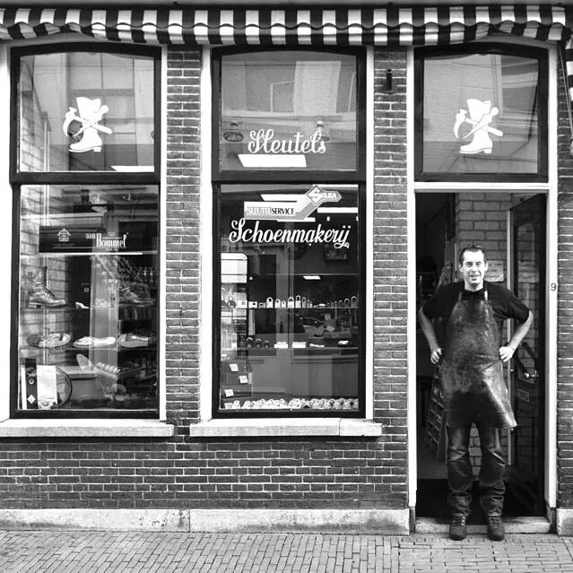 Dennis Deurloo in zijn leren schort in de deuropening van de winkel aan de Vischstraat