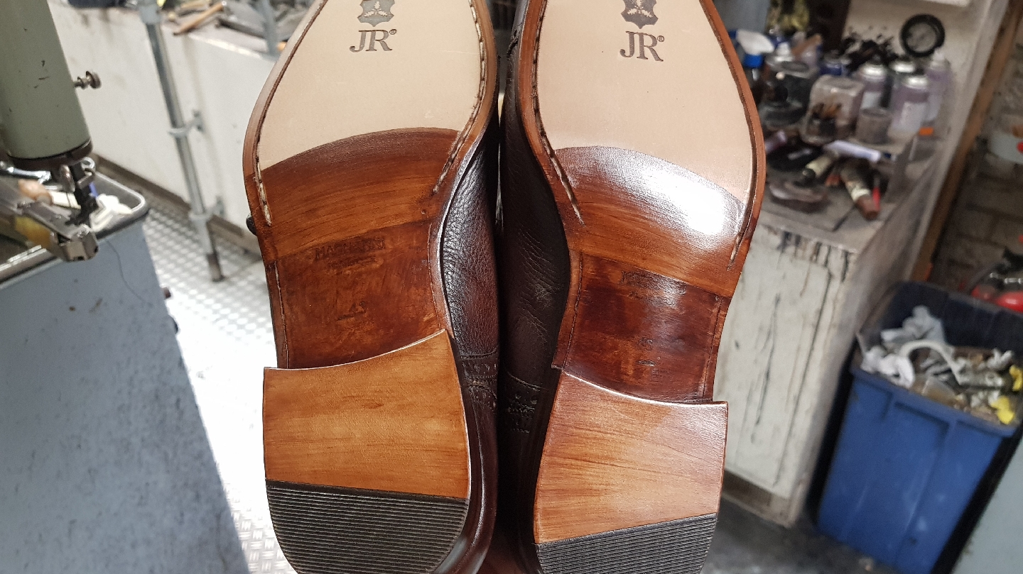 Twee opnieuw gezoolde leren schoenen op de werkbank