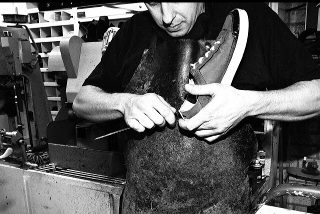 Dennis Deurloo aan het werk aan de werkbank, met een schoen op de leest